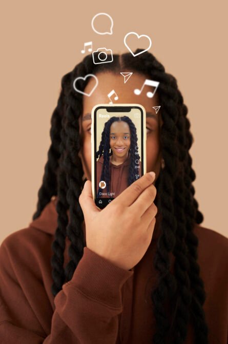 Une community manager dynamique, filmant une story Instagram avec son smartphone dans un espace de coworking lumineux. Autour d'elle, des écrans affichent des analytics et des publications en cours.